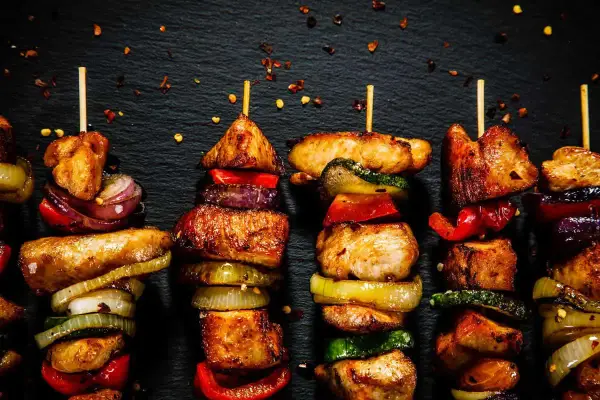 Spiedini di carne succulenti e colorati, alternati a cipolle, peperoni e zucchine, pronti per essere gustati.