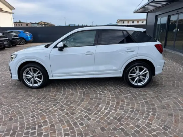 Audi Q2 bianca parcheggiata su pavé. Controlla la pressione pneumatici per un viaggio sicuro.