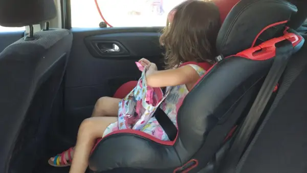 Niña en silla de coche, lista para el viaje. Aún no es el momento cuando puede ir un niño sin silla en el coche.