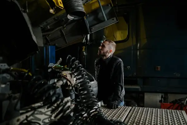 Mechanik analizuje przedmuchy w silniku diesla objawy, badając skomplikowane przewody i elementy ciężarówki w warsztacie.