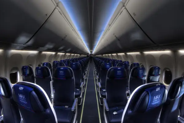 Wnętrze samolotu Boeing 737 MAX 8 LOT, rzędy ciemnych foteli z niebieskimi zagłówkami z logo LOT MAX.