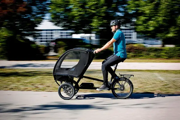 Mann fährt ein Lastenrad mit Kabine, ideal für lastenrad erwachsene transportieren.