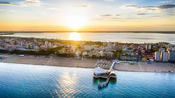 Coucher de soleil sur Lignano, Italie. La plage et la mer s'étendent à perte de vue, avec un pont moderne se jetant dans l'eau.