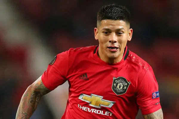 Marcos Rojo w czerwonej koszulce Manchester United, z widocznym logo klubu i sponsora. Jego wiek nie jest widoczny, ale determinacja na twarzy mówi wszystko.