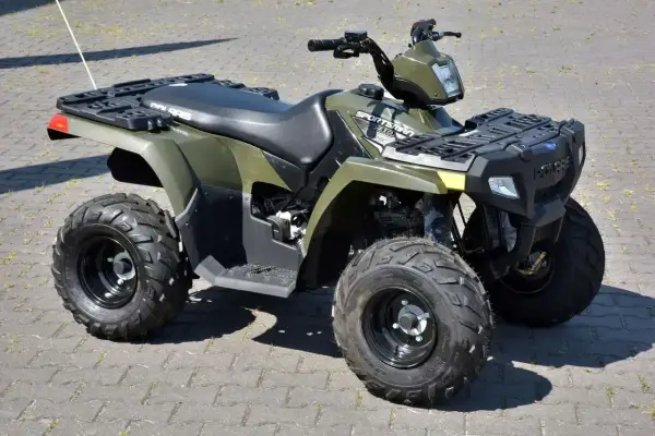 Zielony quad Polaris Sportsman 300 na kostce brukowej.