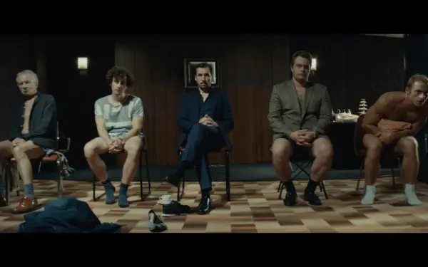 Pięciu mężczyzn siedzi na krzesłach, każdy w innym stroju. Scena z filmu "samiec alfa".
