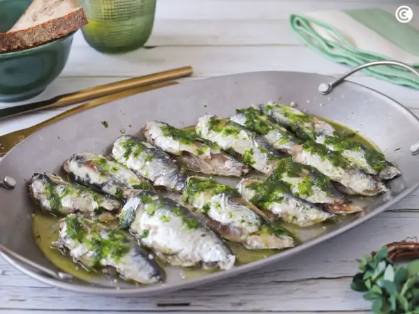 Deliciosas sardinas al horno, cubiertas con una sabrosa salsa verde, listas para disfrutar.