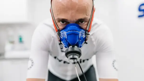 Intensywny trening, badanie **pułapu tlenowego**. Mężczyzna w masce analizującej oddech, skupiony na wysiłku.