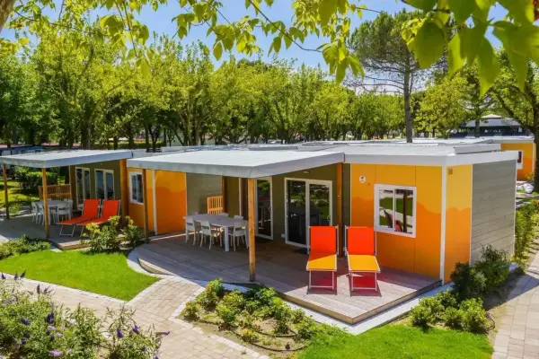 Kolorowe domki na kempingu, z tarasami i leżakami, otoczone zielenią. Prawdziwy camping garden paradiso!