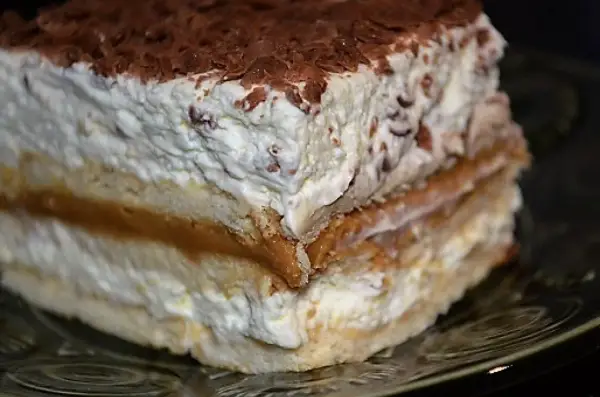 Pyszna krówka bez pieczenia, warstwowa, z kremem i czekoladową posypką, na talerzu.