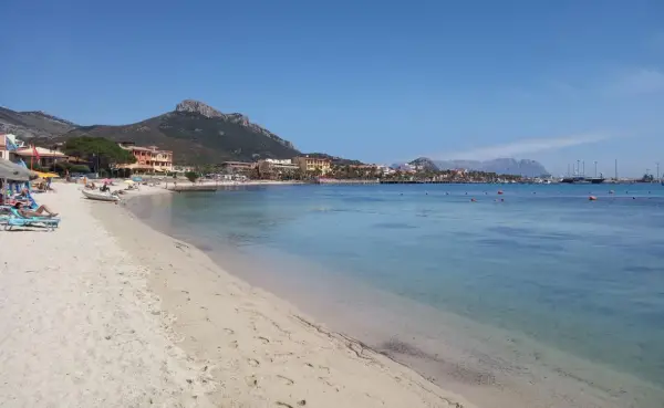 Plage de sable fin, eaux turquoise et montagnes en arrière-plan. Un rêve d'aranci in Sardegna.