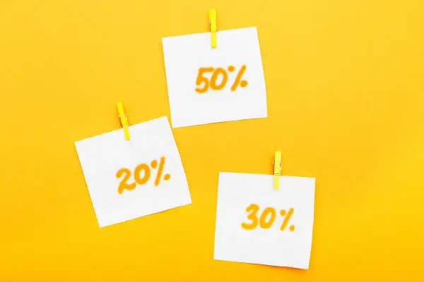 Trzy karteczki z napisami 20%, 30% i 50% przyczepione żółtymi spinaczami. Idealne zniżki dla emerytów!