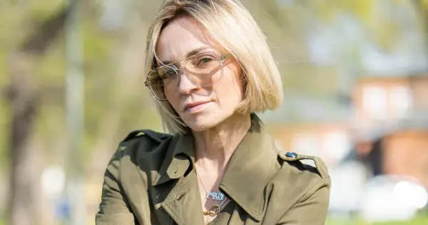 Anna Wyszkoni w okularach i zielonym płaszczu, na tle zieleni.