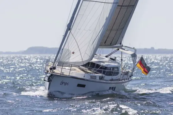 Le voilier Sirius 40 DS "Gryps" navigue sur une mer scintillante, pavillon allemand au vent.