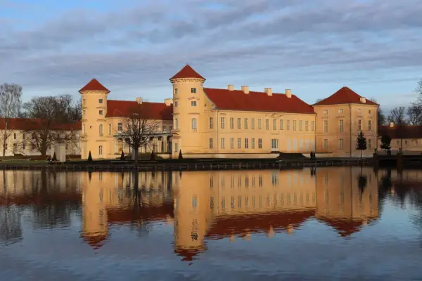 Das Schloss Rheinsberg spiegelt sich im Wasser. Die historische Altstadt von Rheinsberg zeigt sich von ihrer schönsten Seite.
