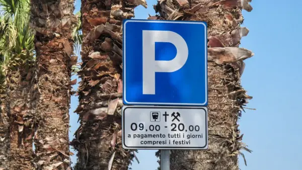 Znaki drogowe we Włoszech: niebieski znak parkingu z literą "P" i tabliczka informująca o płatnym parkingu od 9:00 do 20:00, codziennie, w tym święta.