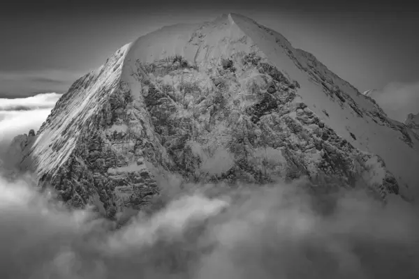 Sommet enneigé émergeant des nuages, une vision spectaculaire capturée par Guido Magnone.