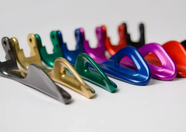 Una fila di moschettoni colorati, con finitura anodizzazione naturale, disposti su sfondo bianco.