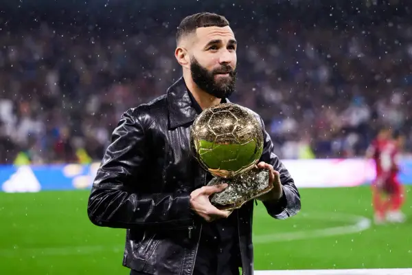 Karim Benzema trzyma Złotą Piłkę, zastanawiając się, ile waży złota piłka.
