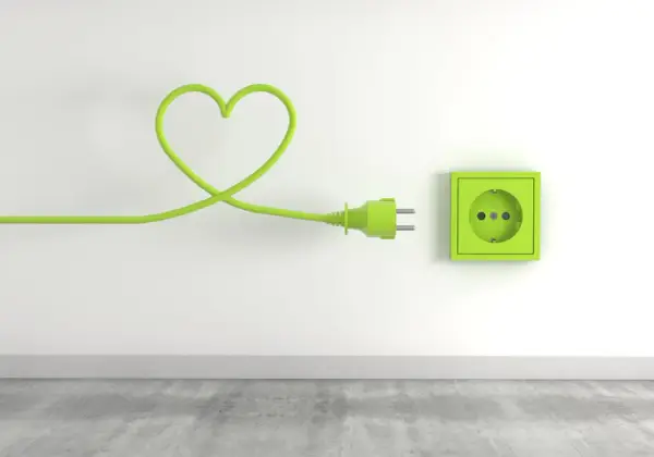 Zielony kabel w kształcie serca podłączony do gniazdka, symbolizujący troskę o niskie opłaty za media.