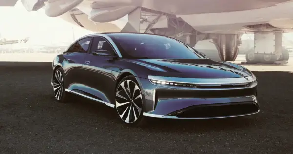 Ciemny sedan Lucid Air na tle samolotu.