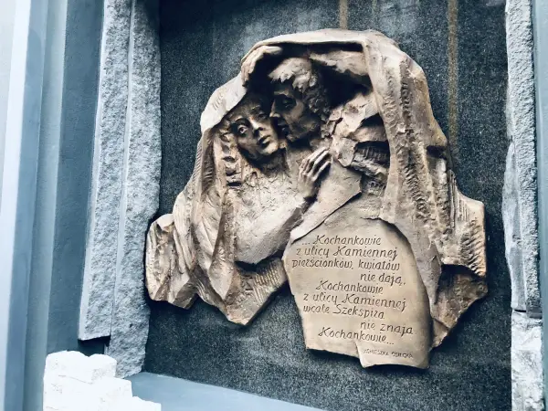 Rzeźba na kamiennej płycie przedstawia przytulonych kochanków. Cytat z Agnieszki Osieckiej mówi o miłości z ulicy Kamiennej.