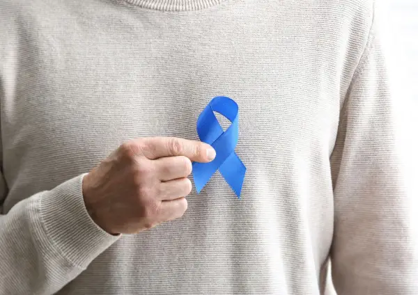 Mężczyzna trzyma niebieską wstążkę symbolizującą świadomość raka prostaty. Rozważamy usunięcie prostaty skutki.
