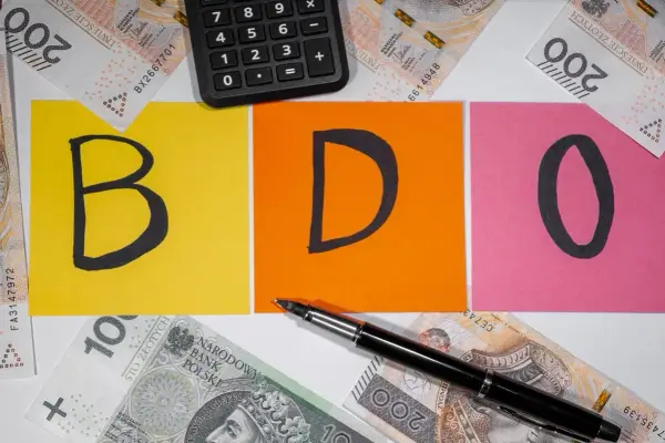BDO - litery na kolorowych kartkach, obok kalkulator i polskie banknoty. Kto nie musi, niech nie liczy.