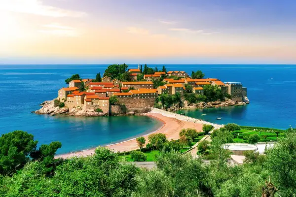 Drömresa till Montenegro: en pittoresk ö med stenhus och röda tak, omgiven av turkost hav. Perfekt för en solsemester.