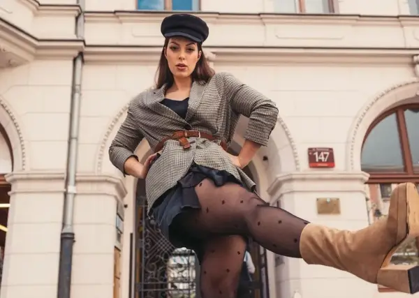 Kobieta w czapce i marynarce w kratę, z nogą uniesioną do przodu. Czy to rozmiar damski 44?