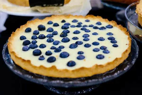 Pyszna tarta z borówkami na kremowym nadzieniu, ozdobiona świeżymi owocami. Idealna na deser.