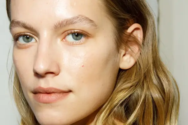 Rostro de mujer con piel luminosa y húmeda, como si acabara de usar bruma facial para que sirve la bruma facial, realzando su belleza natural.