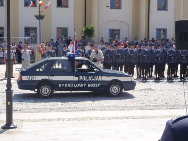 U pana Boga w ogródku obsada: policjanci w mundurach stoją w szeregu obok radiowozu.
