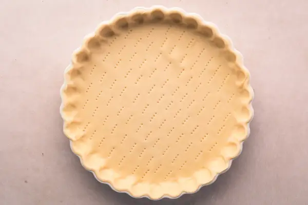 Pâte brisée salée prête à être garnie. Les petits trous préparent la base pour une cuisson parfaite.