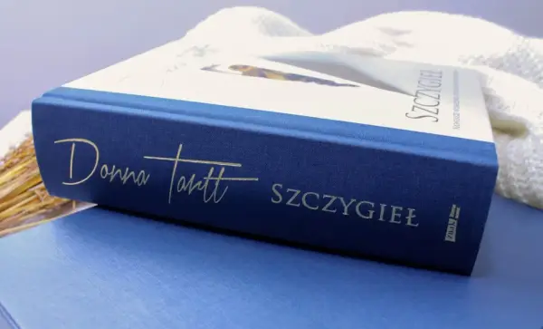 Granatowa okładka książki "Szczygieł" Donny Tartt z wytłoczonym złotym napisem.