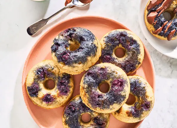 Keto pączki z mąki migdałowej z jagodami na różowym talerzu.