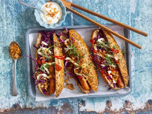 Drei leckere Hotdogs mit Rotkohl, Kresse und Röstzwiebeln – perfekt für vegetarisches Grillen!