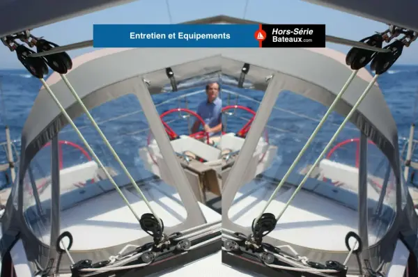 Vue depuis le cockpit d'un voilier, avec un homme au gouvernail. Les cordages et poulies sont visibles, prêts pour une navigation. L'équipement VHF ASN est essentiel pour la sécurité.