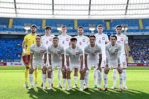 Młodzieżowa reprezentacja Polski w piłce nożnej pozuje do zdjęcia na stadionie.