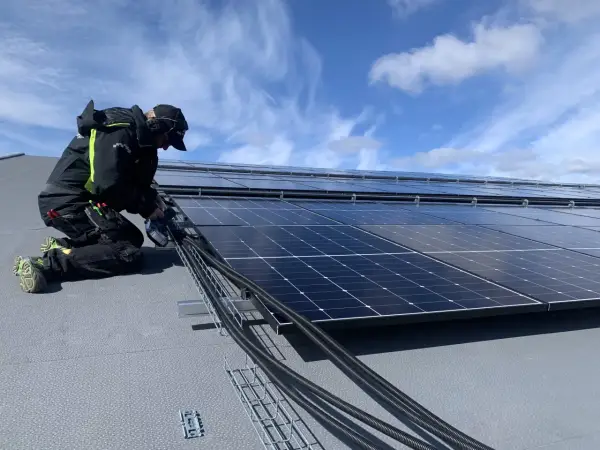 Installatör arbetar med solpaneler, drar kablar. Olika batteri storlekar kan behövas för att optimera energilagringen.