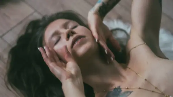 Lilith w byku, z zamkniętymi oczami, dłońmi na twarzy, leży na drewnianej podłodze.