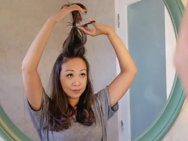 Mujer se corta el pelo en casa, creando un corte de pelo a capas.