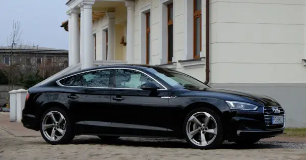 Eleganckie, czarne Audi A5 z 2018 roku zaparkowane przed klasycznym budynkiem z kolumnami.