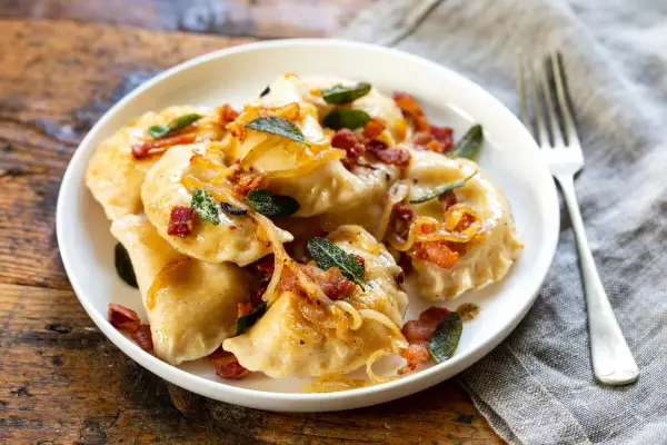 Pyszne pierogi z boczkiem i cebulką, idealne na obiad. Dowiedz się, ile gotować pierogi, by były idealne.