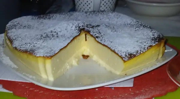 Puszysty sernik z airfryer, oprószony cukrem pudrem, z lekko przypieczoną skórką i kremowym wnętrzem.