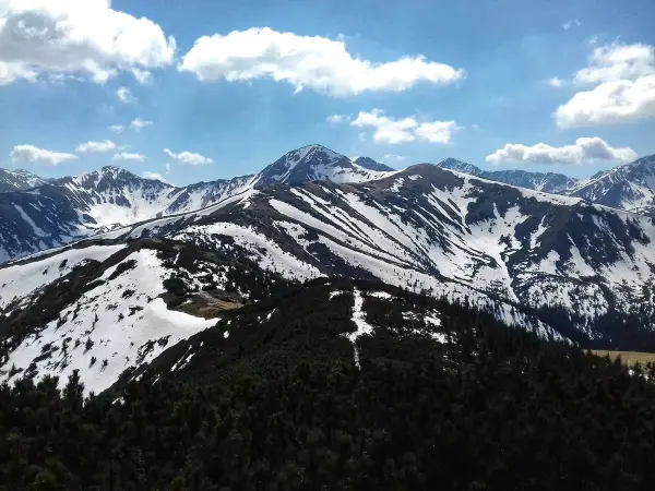 Majestatyczne Tatry w kwietniu, pokryte śniegiem szczyty i zielone lasy.