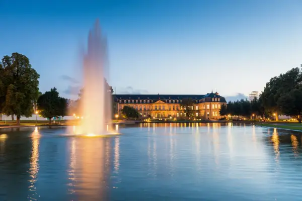 Ein beleuchteter Brunnen spiegelt sich im Wasser vor dem Neuen Schloss in der Stuttgarter Innenstadt.