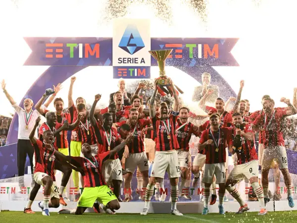 Piłkarze świętują zdobycie scudetto, unosząc puchar Serie A wśród konfetti i fajerwerków.