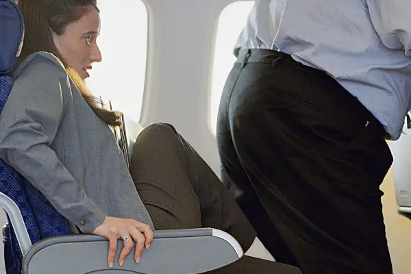 Kobieta siedzi w samolocie Ryanair, obok niej przechodzi pasażer. Zastanawiasz się, ile cm ma pas w samolocie Ryanair?
