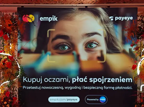Reklama Empiku z hasłem "Kupuj oczami, płać spojrzeniem". Pokazuje zbliżenie na zielone oczy młodej kobiety, sugerując innowacyjne metody płatności Payeye.